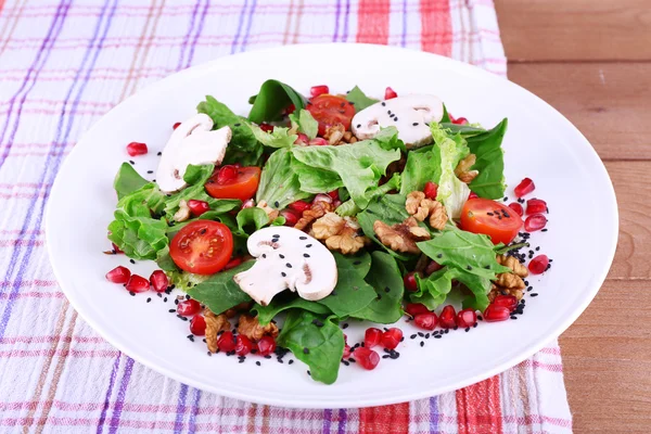 Fresh salad with greens, garnet and spices on plate on table close-up — Stock Photo, Image