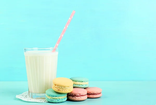 Assortimento di delicati macaron colorati e vetro con latte su sfondo di legno a colori — Foto Stock