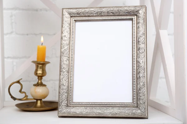 Photo frame op plank met kandelaar op bakstenen muur achtergrond — Stockfoto