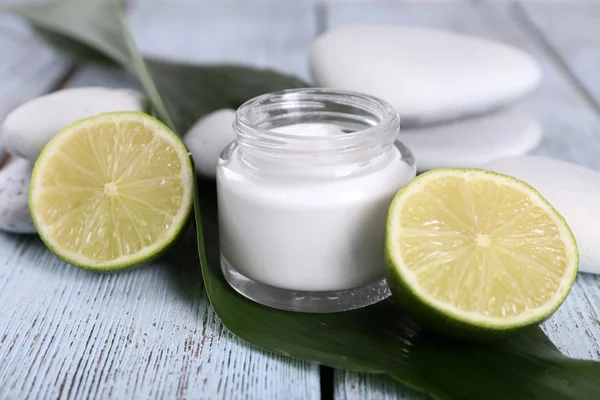 Crema cosmética con media cal y piedras de spa sobre fondo de madera — Foto de Stock