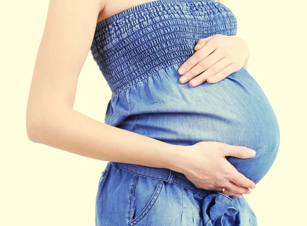 Bela jovem grávida tocando sua barriga no fundo de luz — Fotografia de Stock