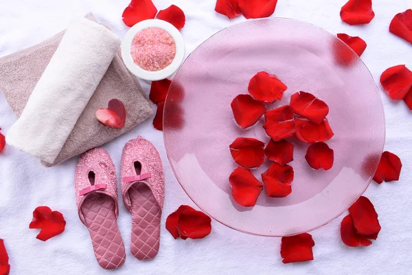 Cuenco spa con agua, pétalos de rosa, toalla y zapatillas sobre fondo claro. Concepto de pedicura o tratamiento de spa natural — Foto de Stock