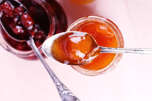 Gläser mit schmackhafter Marmelade auf hölzernem Hintergrund — Stockfoto