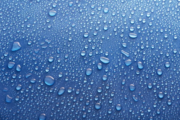 Water drops on glass on blue background — Stock Photo, Image