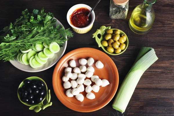 Queijo mussarela com azeitonas e verduras sobre fundo de madeira — Fotografia de Stock