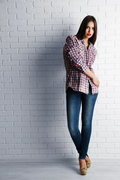 Pretty girl dressed in casual style posing on white brick wall background — Stock Photo, Image