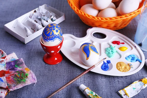 Painting Easter eggs on colorful tablecloth background — Stock Photo, Image