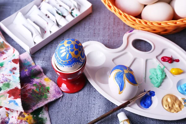 Painting Easter eggs on colorful tablecloth background — Stock Photo, Image