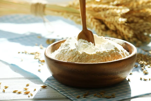 Bowl of flour with spoon and napkin on wooden table, closeup — Stock Photo, Image