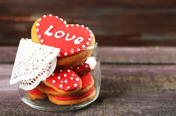 Biscotti a forma di cuore per il giorno di San Valentino in vaso di vetro su sfondo di legno colore — Foto Stock