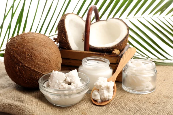 Coco con frascos de aceite de coco y crema cosmética sobre tela de saco sobre fondo natural — Foto de Stock
