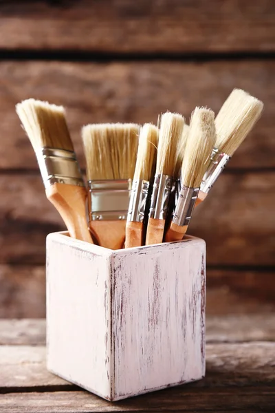 Paint brushes on old wooden background — Stock Photo, Image