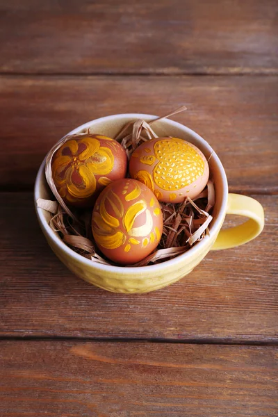 Huevos de Pascua en taza sobre fondo de madera — Foto de Stock
