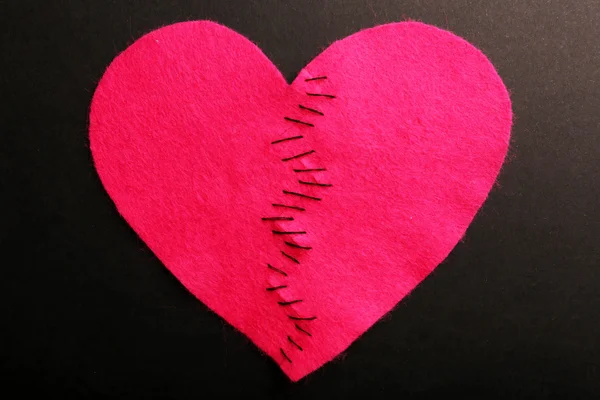 Broken heart stitched from two pieces on black background — Stock Photo, Image