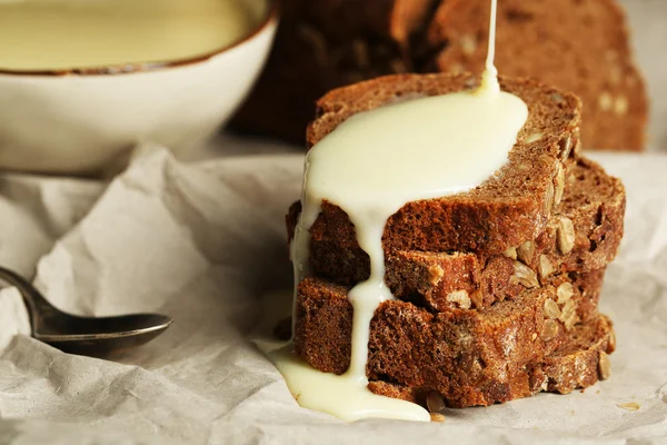 Sneetjes brood met gecondenseerde melk op papier achtergrond — Stockfoto