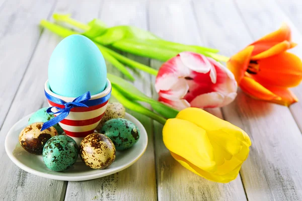 Easter egg in holder and tulip flowers on wooden background — Stock Photo, Image