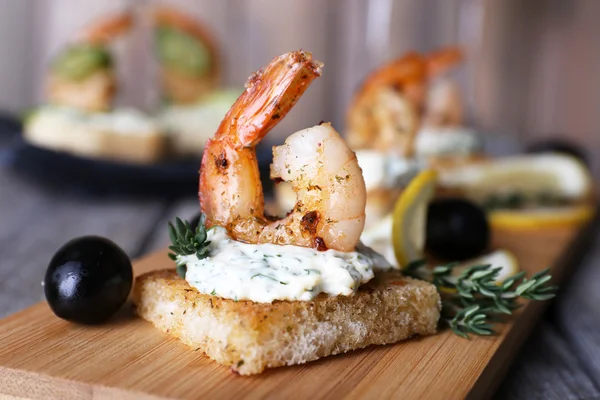 Meze kanepe ile karides ve zeytin masada kesme tahtası üzerinde kapat — Stok fotoğraf