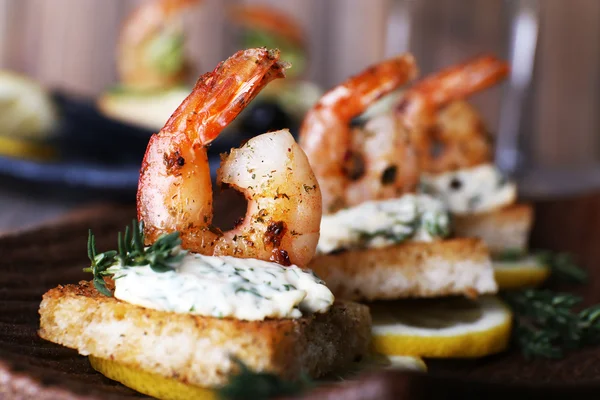 Appetizer canape with shrimp and lemon on plate on table close up — Stock Photo, Image