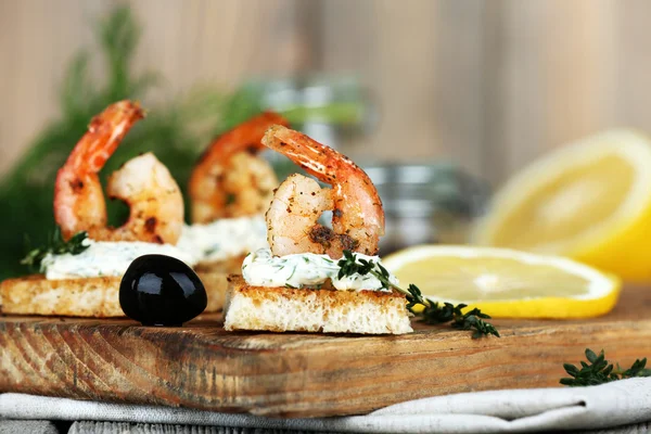 Appetizer canapé com camarão e limão na tábua de corte na mesa de perto — Fotografia de Stock