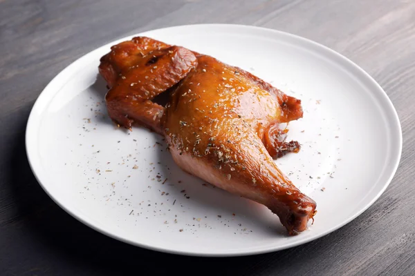 Smoked chicken leg on plate on wooden background — Stock Photo, Image