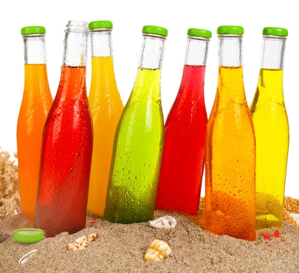 Garrafas de bebida saborosa em areia isolada em branco — Fotografia de Stock