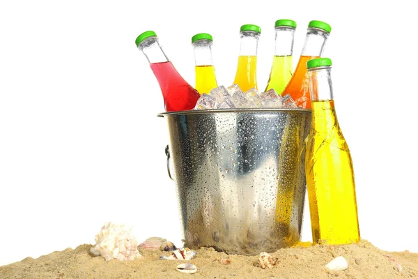 Flessen van smakelijke drank in de metalen emmer met ijs op zand geïsoleerd op wit — Stockfoto