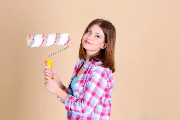 Beautiful girl with roller near wall — Stock Photo, Image