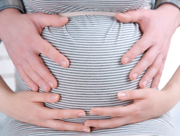 Unga gravid kvinna med man vidrör magen på nära håll — Stockfoto
