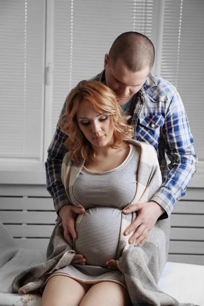 Молодая беременная женщина сидит с мужем в комнате — стоковое фото