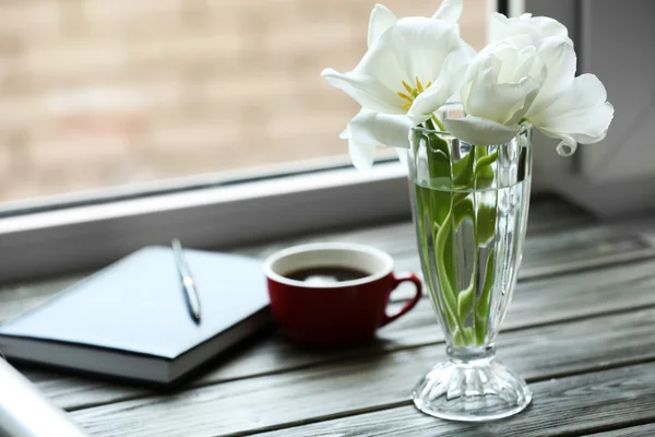 Carnet avec tasse de thé et tulipes blanches dans un vase sur le rebord de la fenêtre — Photo