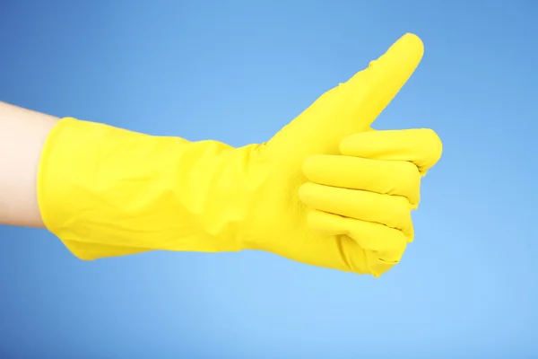 Guante de goma en la mano, sobre fondo azul — Foto de Stock