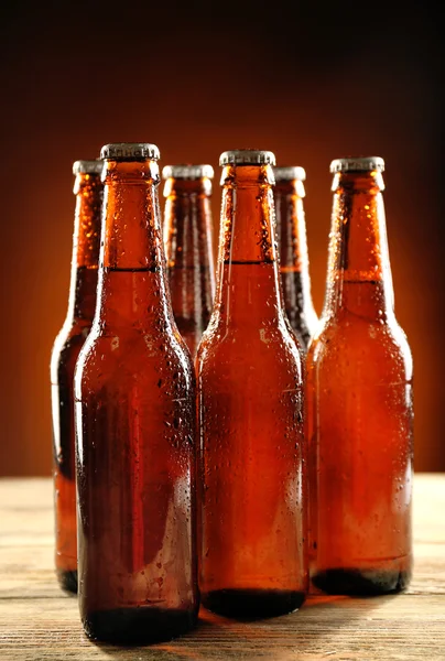 Bouteilles de bière en verre sur table en bois sur fond sombre — Photo