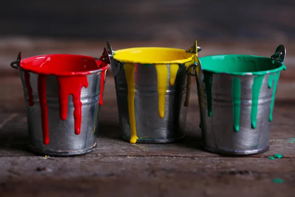 Baldes de metal com tinta colorida sobre fundo de madeira — Fotografia de Stock