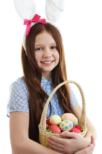 Schönes kleines Mädchen mit Osterhasenohren und Weidenkorb mit Ostereiern, isoliert auf weiß — Stockfoto