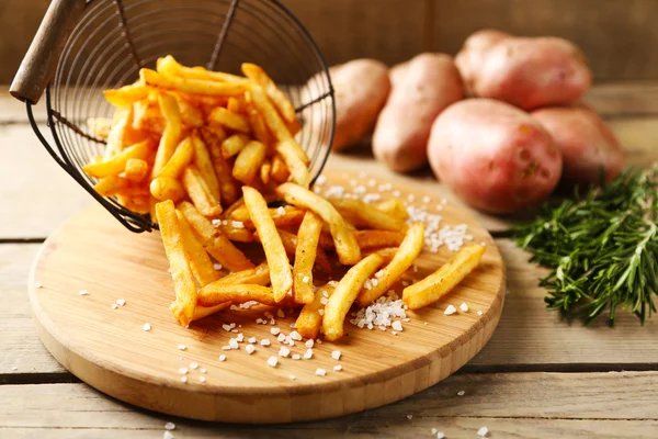 Saboroso batatas fritas em cesta de metal no fundo da mesa de madeira — Fotografia de Stock