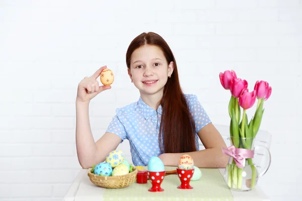 Cute girl decorates Easter eggs, on light background — Stock Photo, Image