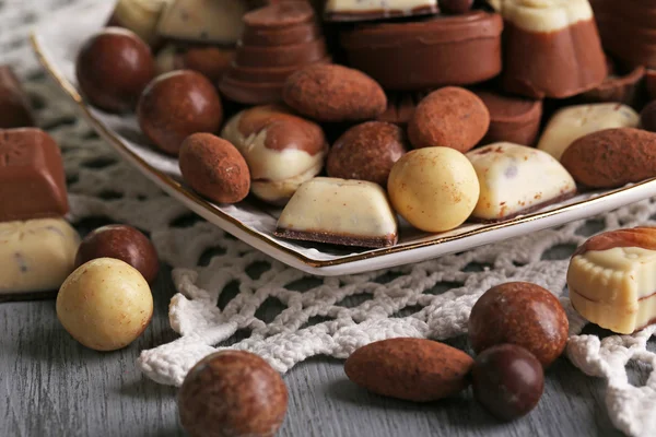 Różnego rodzaju czekoladki na tabliczce na drewnianym stole — Zdjęcie stockowe