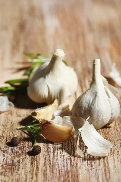 Rauwe knoflook en kruiden op houten tafel — Stockfoto