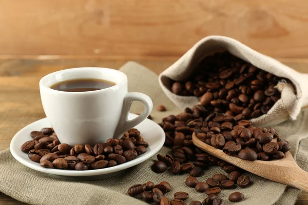 Tasse Kaffee mit Bohnen auf rustikalem Holzgrund — Stockfoto