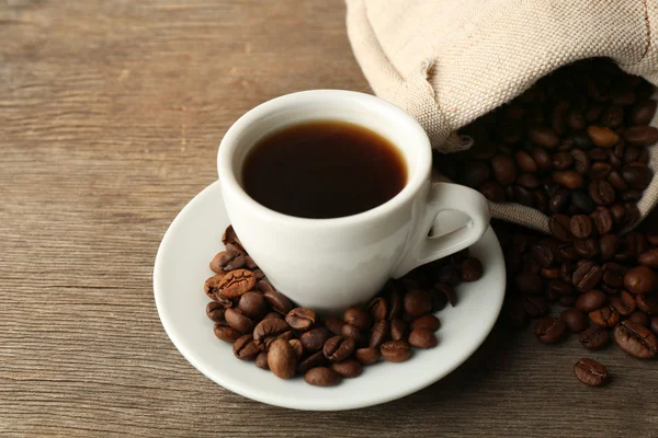 Taza de café con frijoles sobre fondo rústico de madera — Foto de Stock