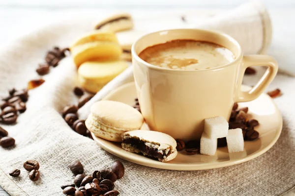 Macaroons coloridos suaves e café na caneca na cor de fundo de madeira — Fotografia de Stock