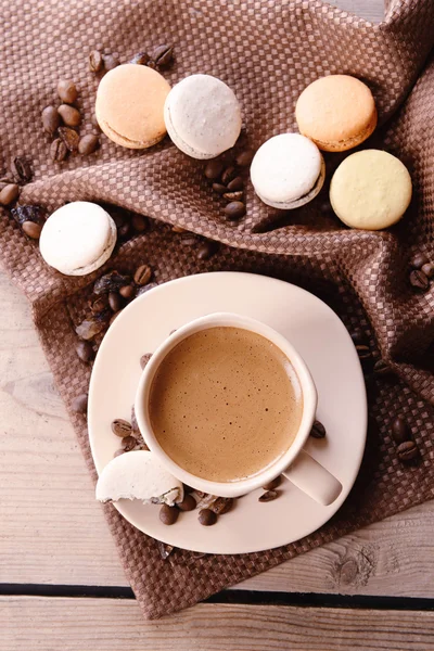 Makaroni yang lembut dan berwarna-warni dan kopi dalam cangkir pada latar belakang meja kayu — Stok Foto
