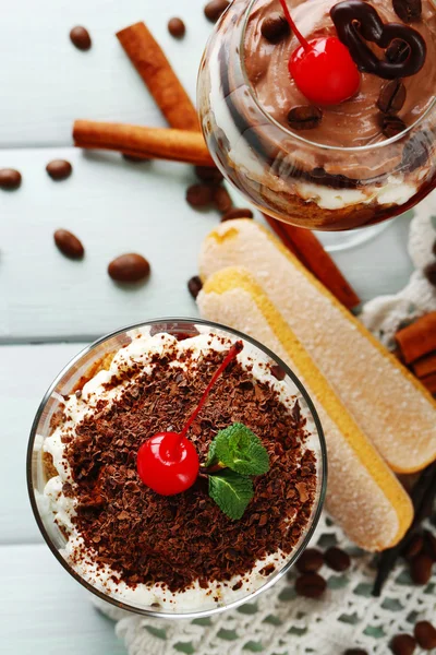 Вкусный десерт тирамису в стаканах, на салфетке, на деревянном фоне — стоковое фото