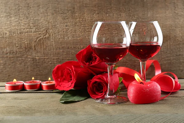 Composição com vinho tinto em copos, rosas vermelhas e coração decorativo em fundo de madeira — Fotografia de Stock