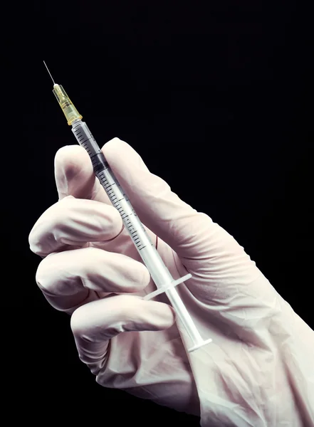 Hands in gloves with syringe on black background — Stock Photo, Image