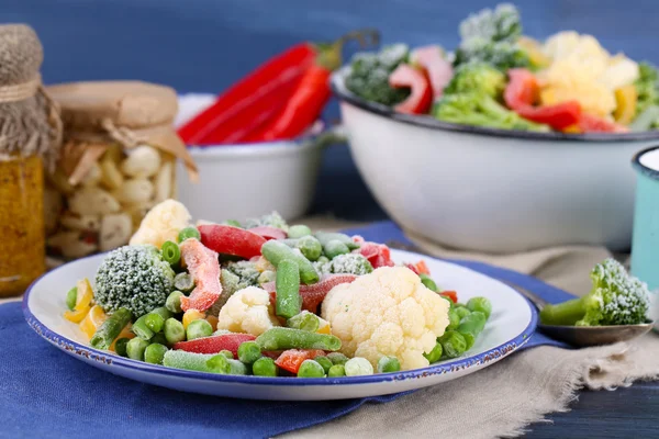 Frozen vegetables on plate on napkin, on wooden table background — Stock Photo, Image