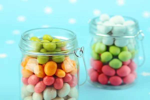 Caramelle multicolore in barattoli di vetro su sfondo colorato — Foto Stock