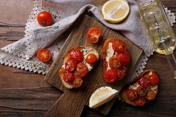 Rebanadas de pan tostado blanco con tomates enlatados y lima sobre tabla de cortar sobre fondo de mesa de madera — Foto de Stock