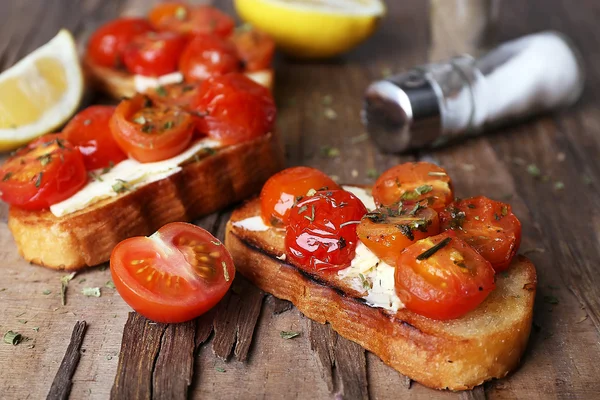 Rebanadas de pan tostado blanco con tomates enlatados y lima sobre mesa de madera, primer plano —  Fotos de Stock