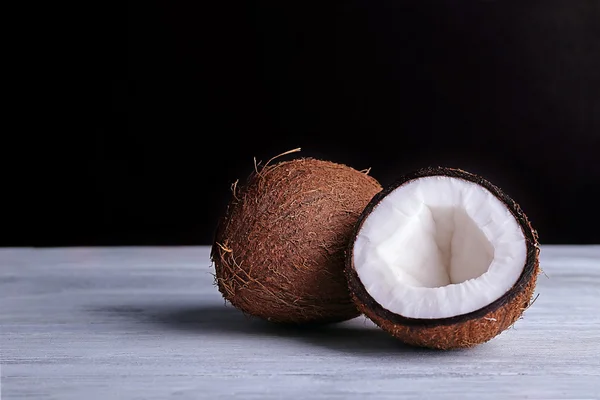 Noix de coco coupée en deux sur table en bois de couleur et fond sombre — Photo